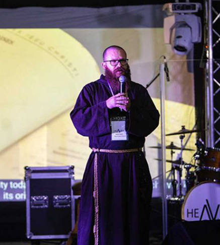 Friar speaking with microphone on stage