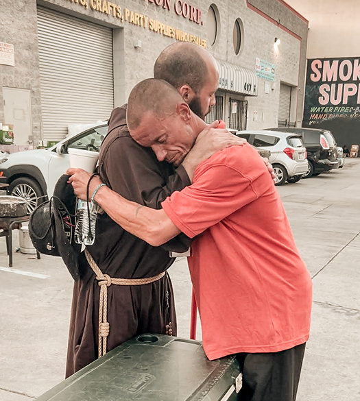 A deep hug between a friar and a young man