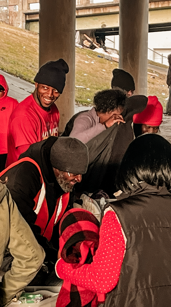 Friars serving and welcoming people under a bridge