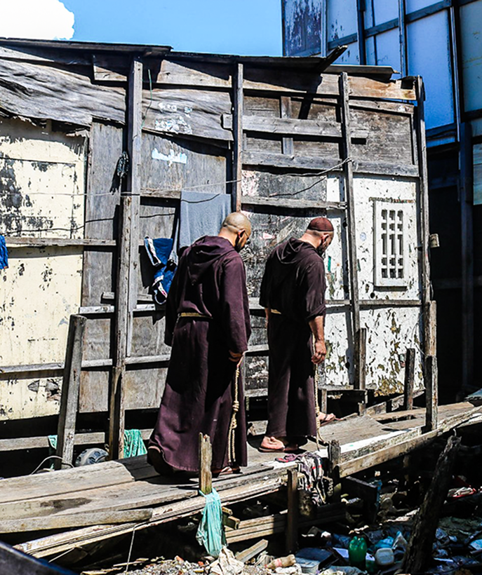 Friars walking in a poor community